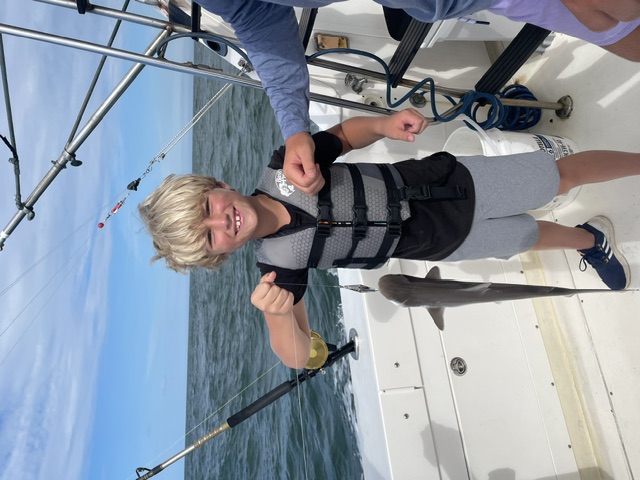 Kid holding a shark catch on the boat
